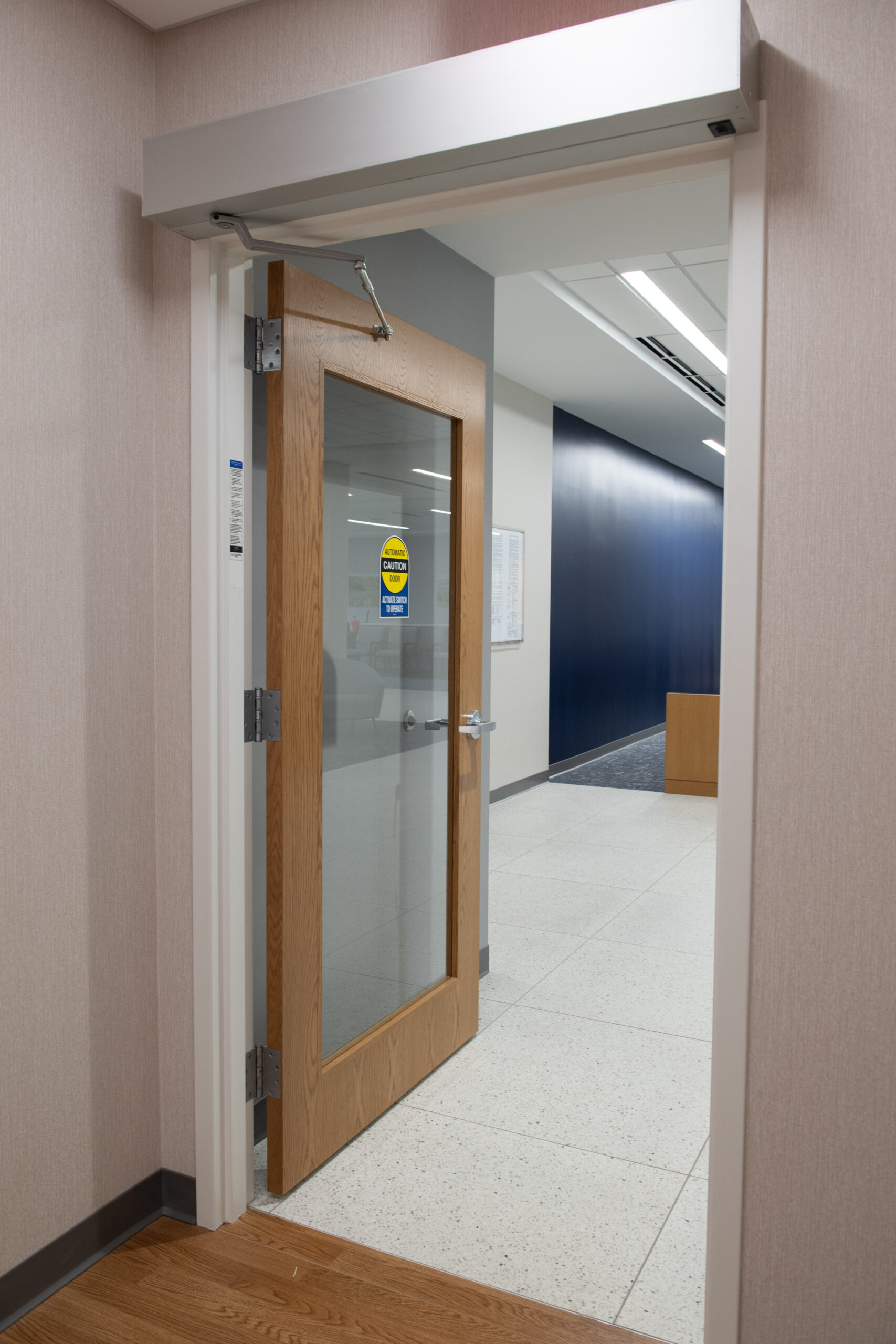 Interior wood and glass door leading to a commercial corridor with glazing features.